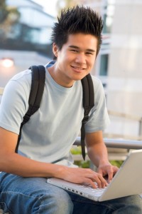 Male student using laptop outside